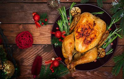 Baked turkey or chicken. The Christmas table is served with a turkey, decorated with bright tinsel and candles. Fried chicken, table. Christmas dinner. Flat lay. Top view